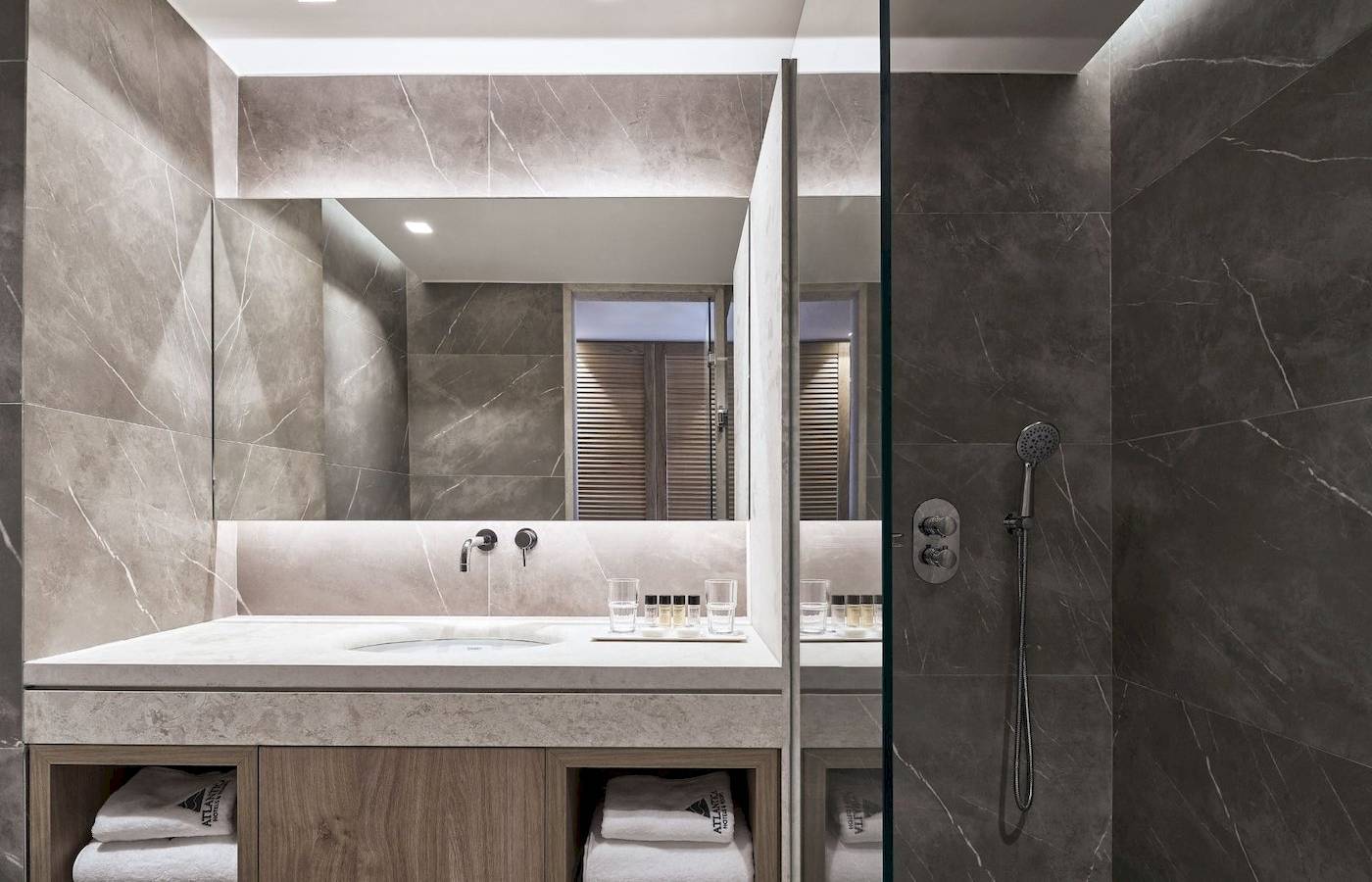 Modernes Badezimmer im Atlantica Beach Resort Kos mit grauen Marmorwänden und einer großen Spiegelfläche.