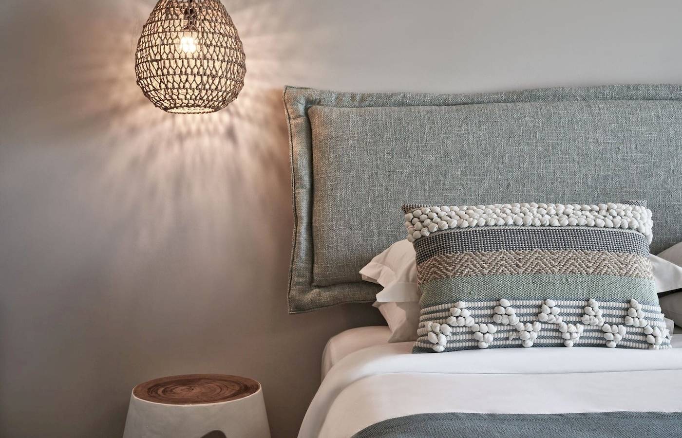 Bett im Atlantica Beach Resort Kos mit Kissen und Lampenschirm.