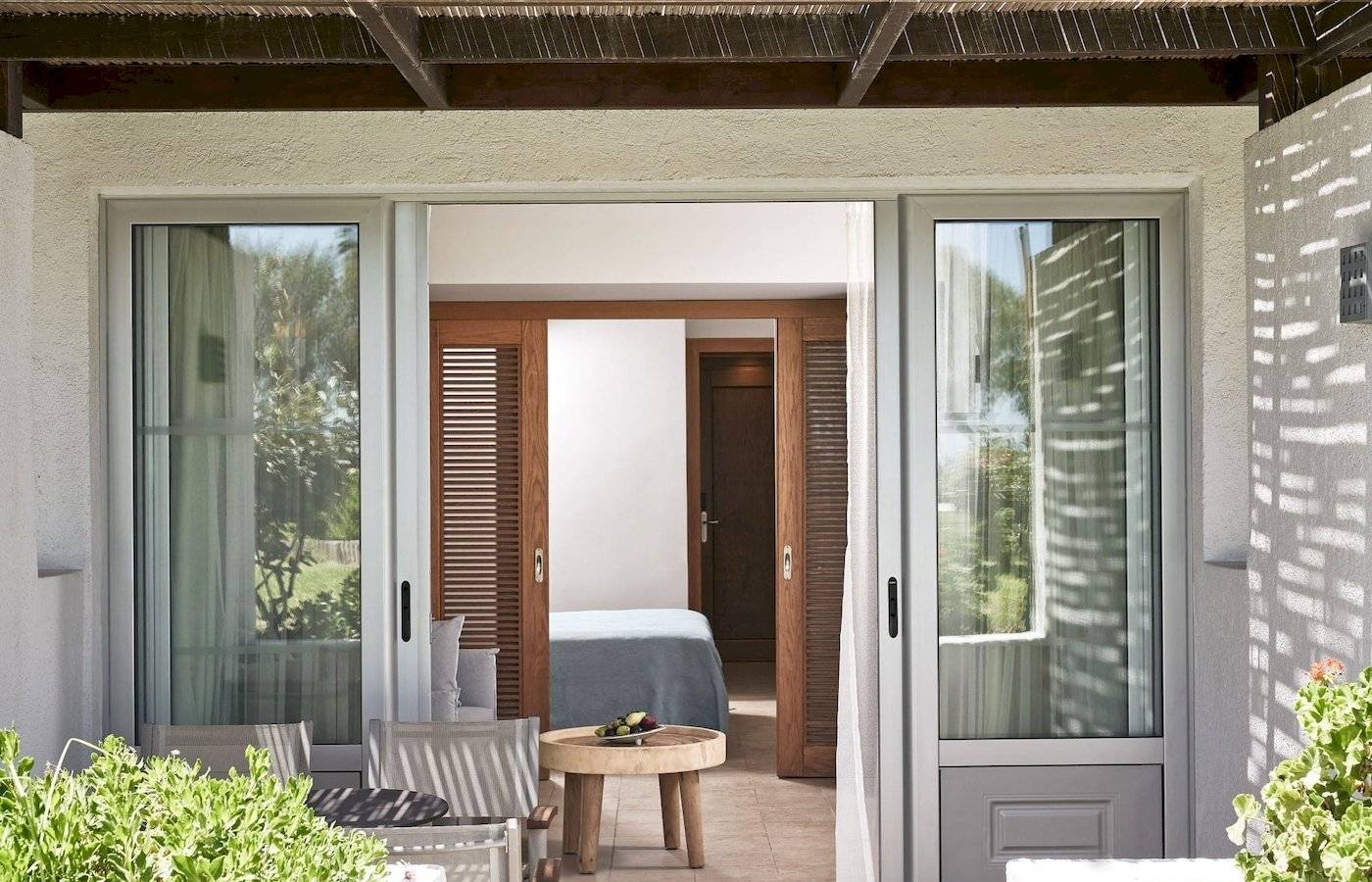 Zimmereingang des Atlantica Beach Resort Kos mit offenem Eingang, Tisch und Pflanzen.