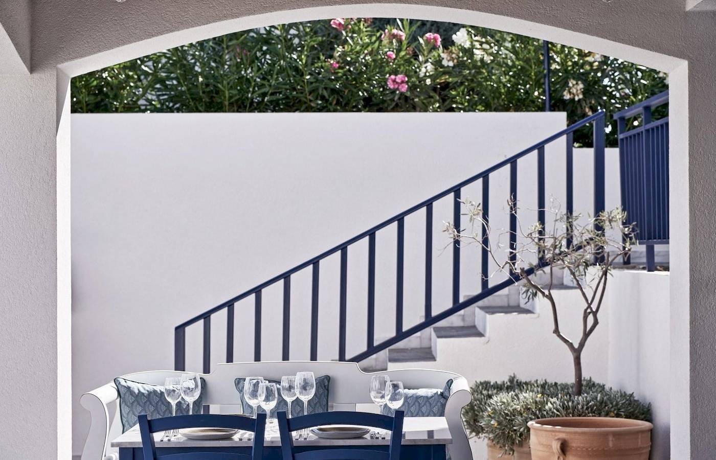 Sitzecke im Garten des Atlantica Beach Resort Kos mit blauen Stühlen und Tisch.