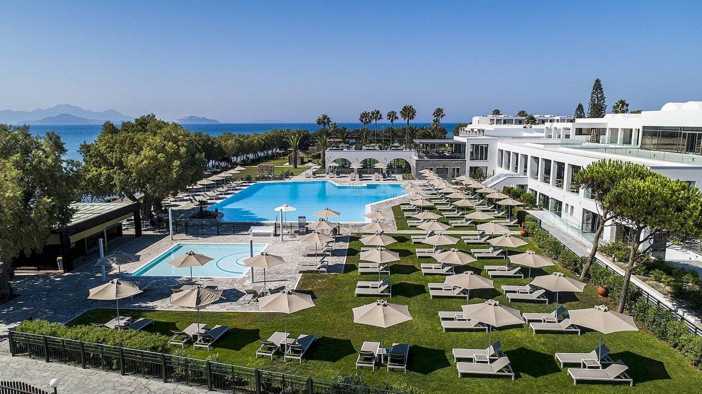 Luftaufnahme des Atlantica Beach Resort Kos mit Swimmingpool, Liegestühlen und Sonnenschirmen