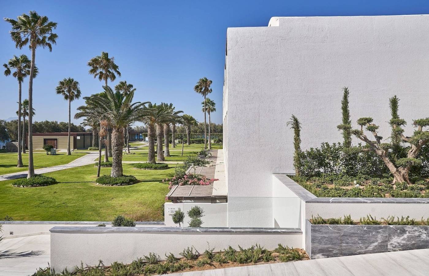 Außenbereich des Atlantica Beach Resort Kos mit weißen Gebäuden und Palmen