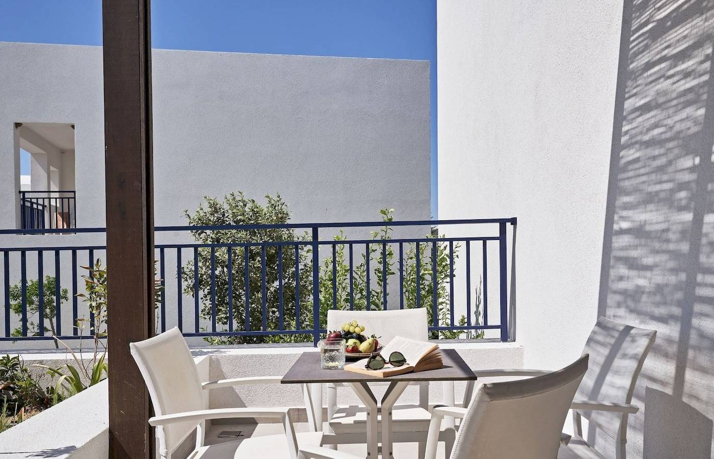 Balkon des Atlantica Beach Resort Kos mit Tisch und weißen Sesseln vor blauem Geländer.