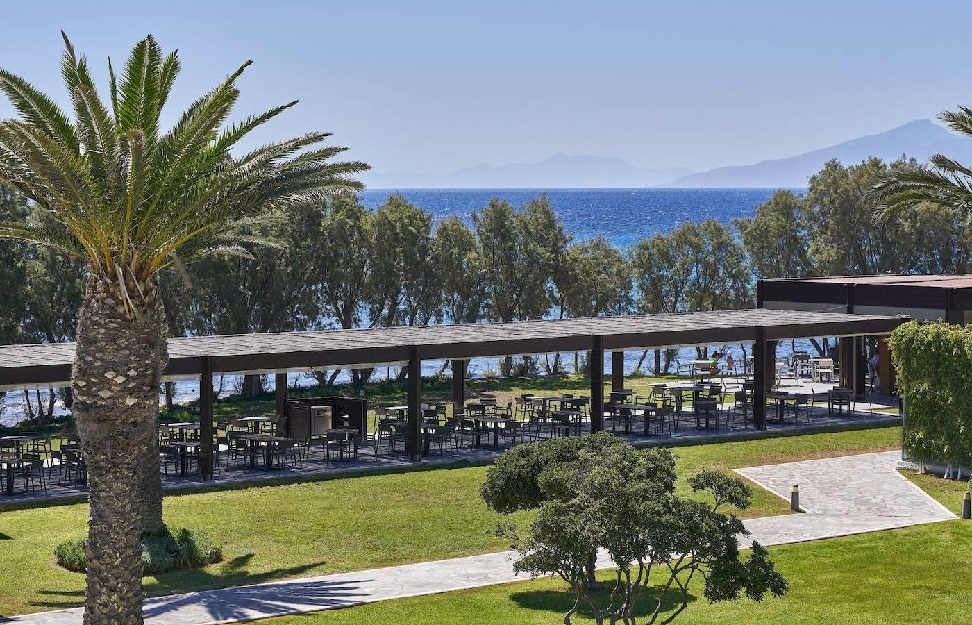 Außenbereich des Atlantica Beach Resort Kos mit Terrasse und Blick auf den Ozean.