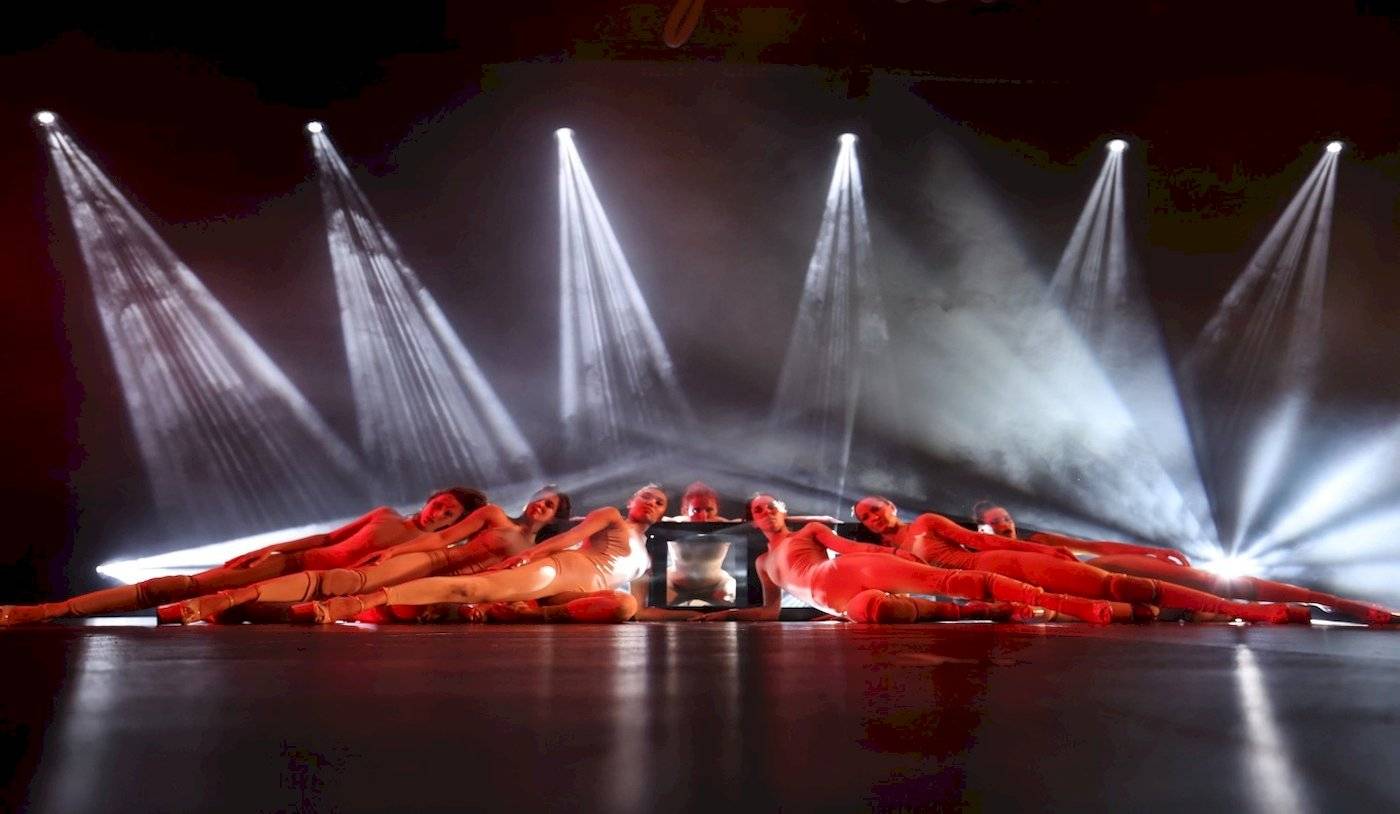 Ein Tanzteam liegt auf der Bühne unter Scheinwerfern und wird fotografiert.