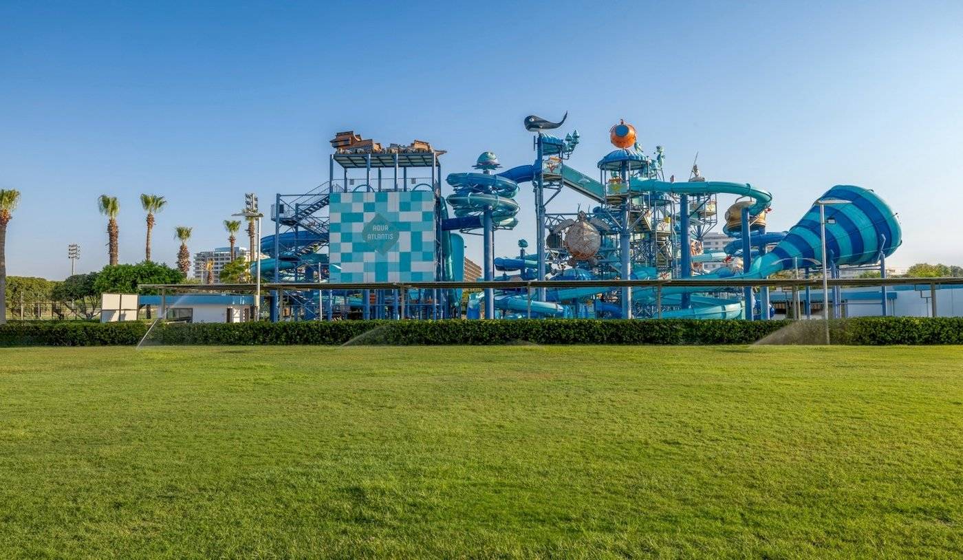 Wasserpark Aqua Atlantis mit großen blauen Rutschen und grüner Rasenfläche