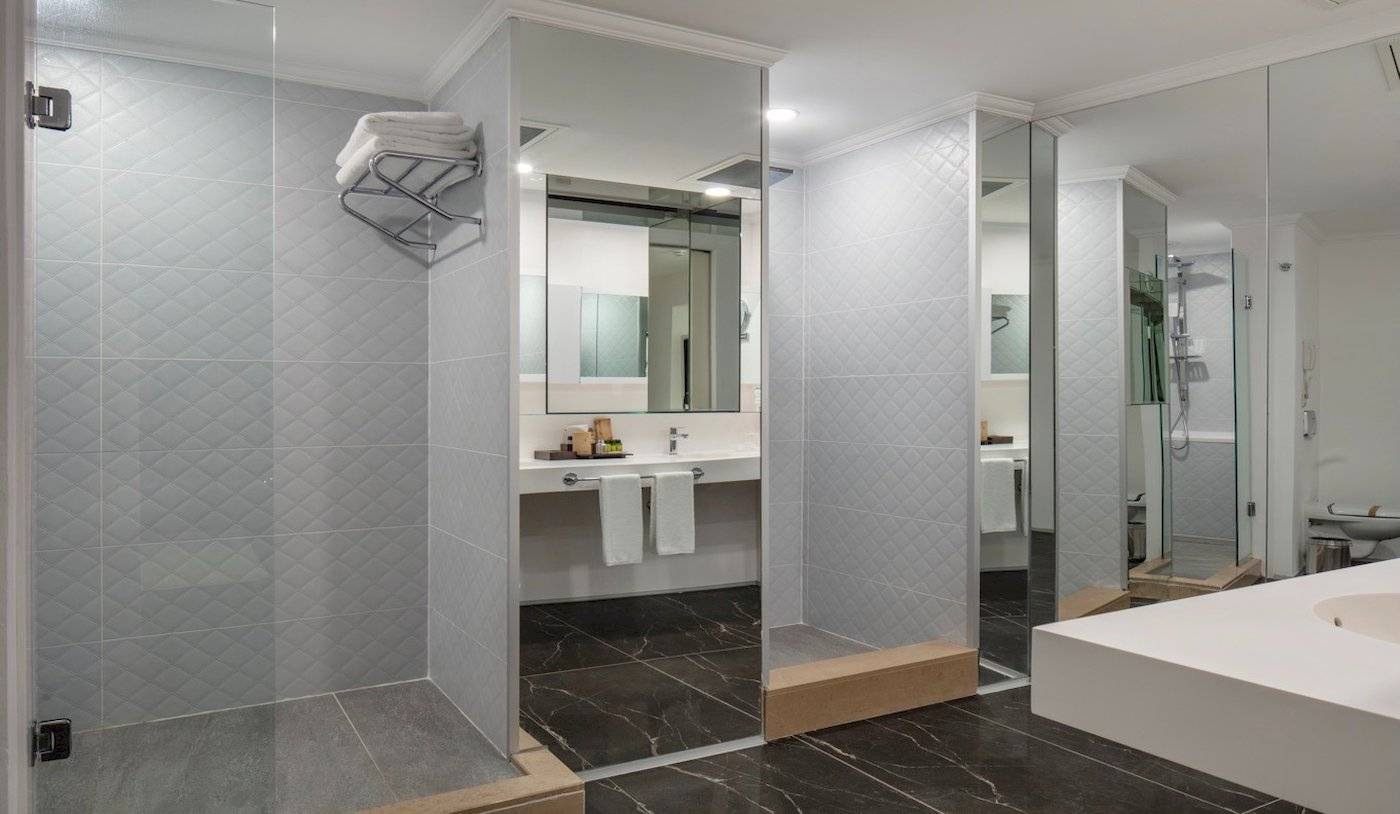 Badezimmer im Nirvana Cosmopolitan Hotel mit Marmorboden, Glasdusche und Badewanne.