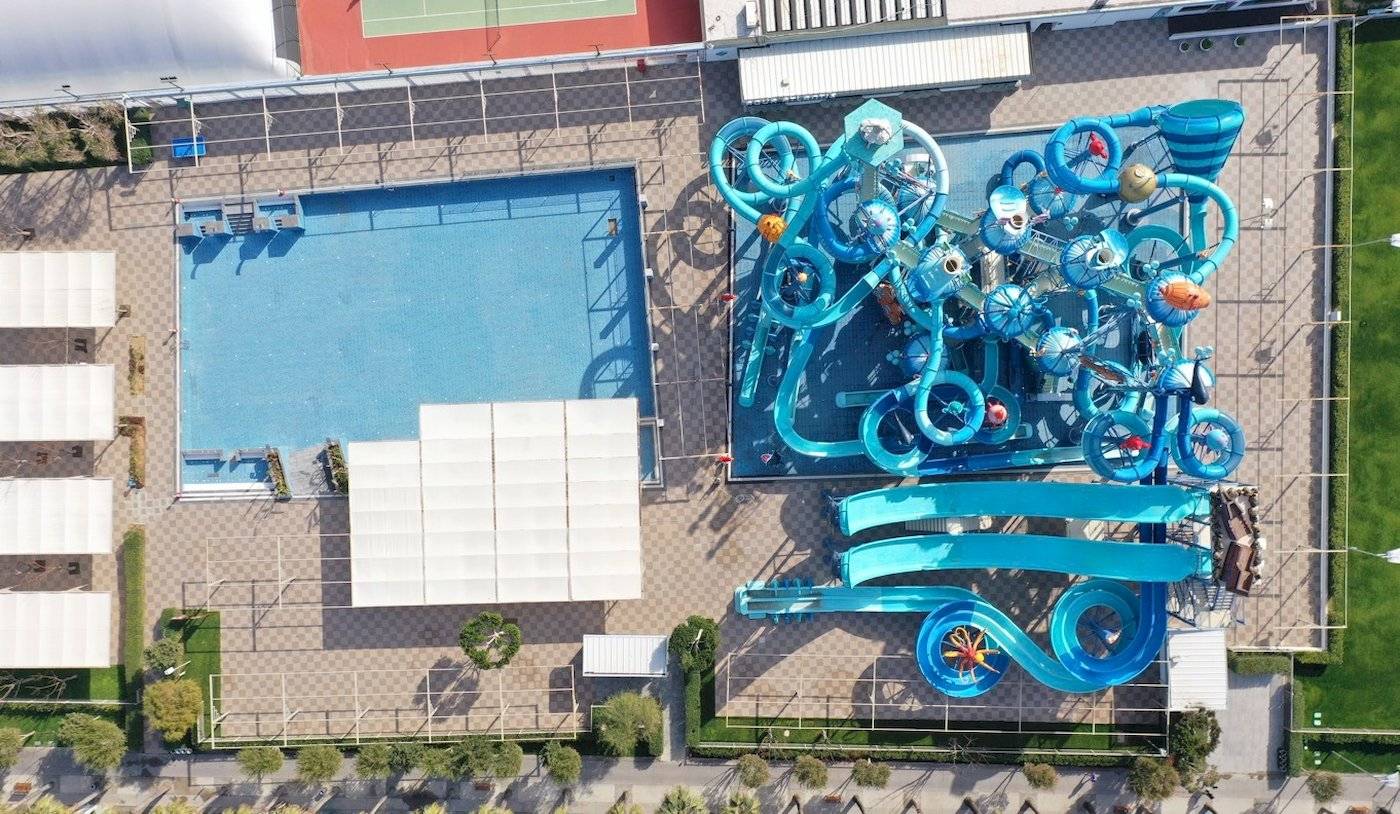 Luftaufnahme des Nirvana Cosmopolitan Hotels zeigt einen großen Wasserpark mit blauen Rutschen und einem großen Schwimmbad.