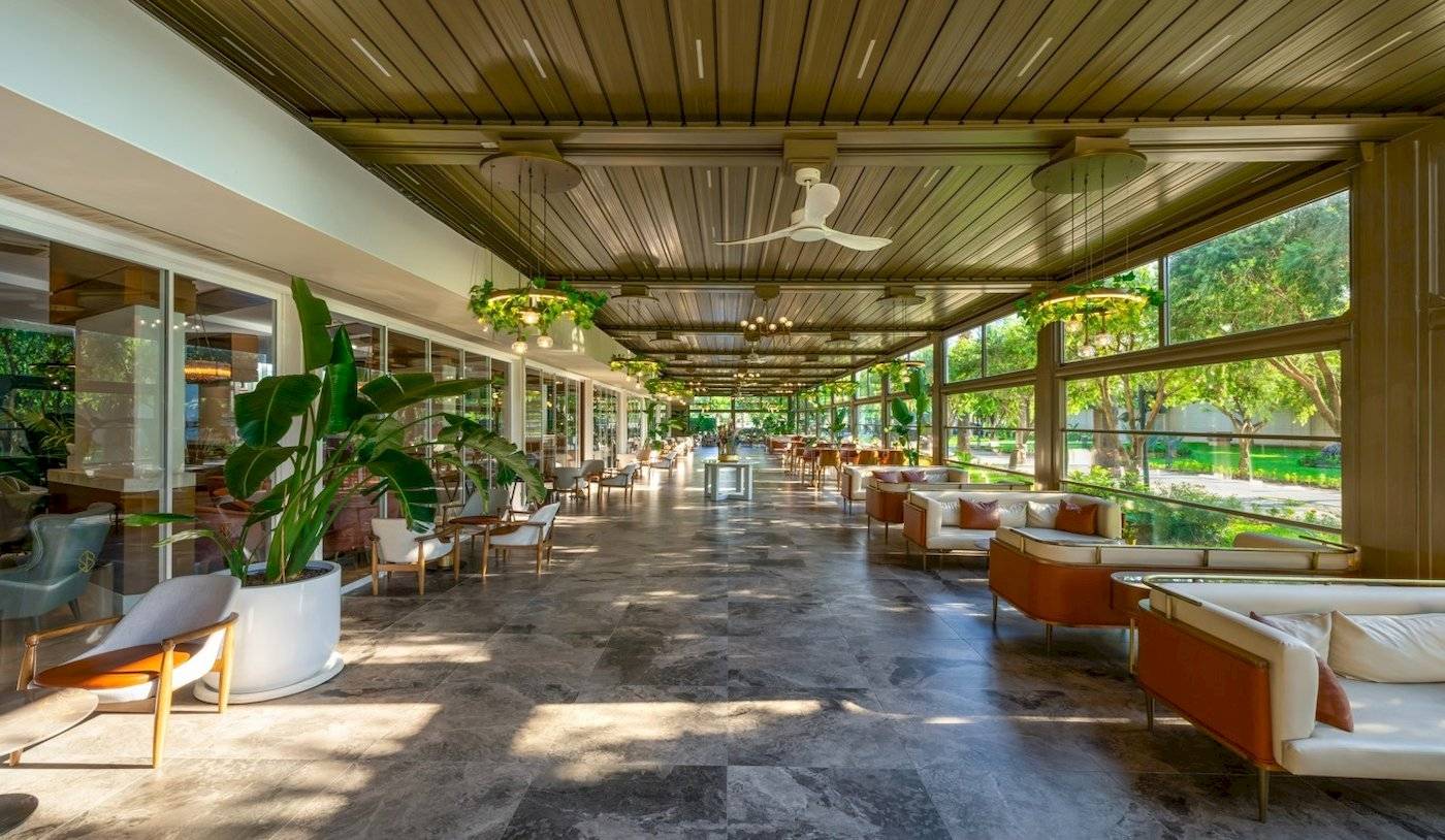 Innenbereich des Nirvana Cosmopolitan Hotels mit Sofas, Tischen, Pflanzen und Deckenventilatoren.