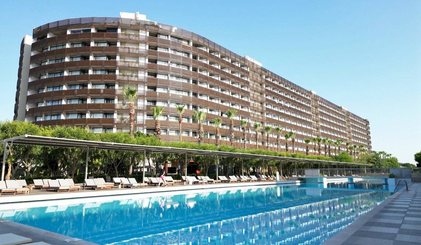 Das Nirvana Cosmopolitan Hotel mit einem großen Swimmingpool und Sonnenliegen davor.