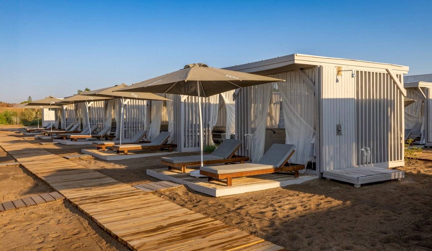Reihe von Strandlounges mit Sonnenschirmen und Sonnenliegen auf einem Holzsteg