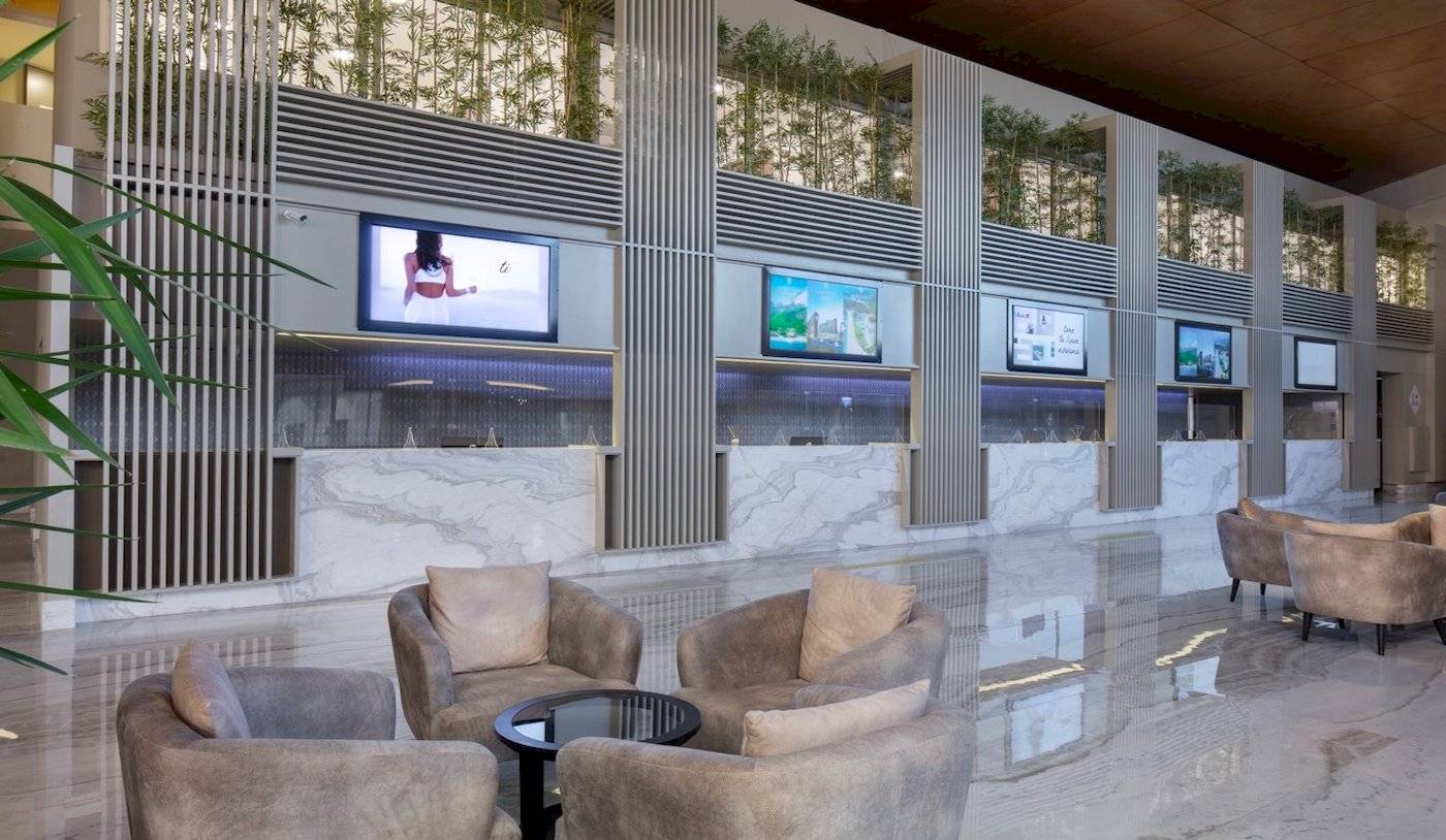 Lobby-Sitzbereich des Nirvana Cosmopolitan Hotels mit Marmorboden und Monitoren.