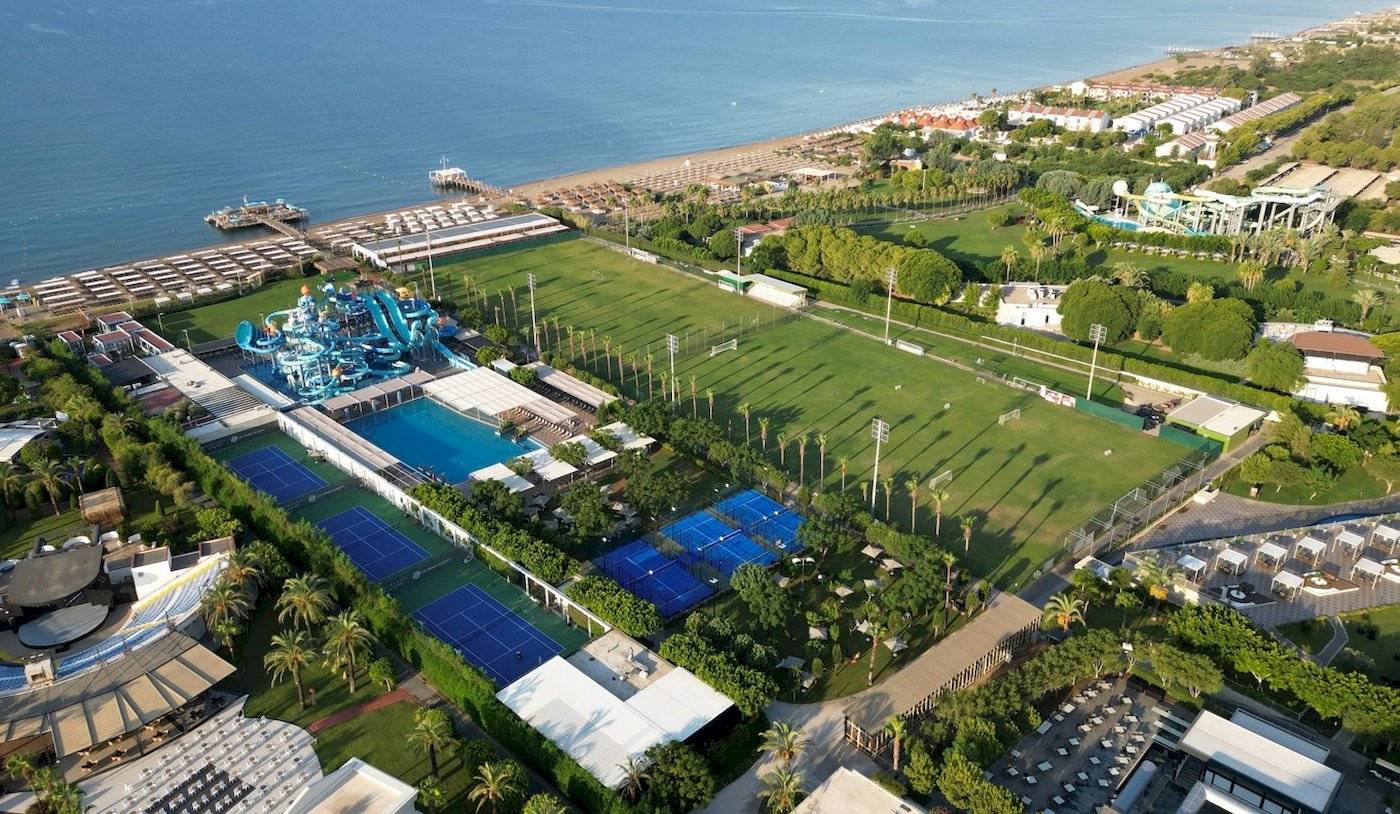 Luftbild des Nirvana Cosmopolitan Hotels mit Wasserrutsche, Tennisplätzen und Meer im Hintergrund.