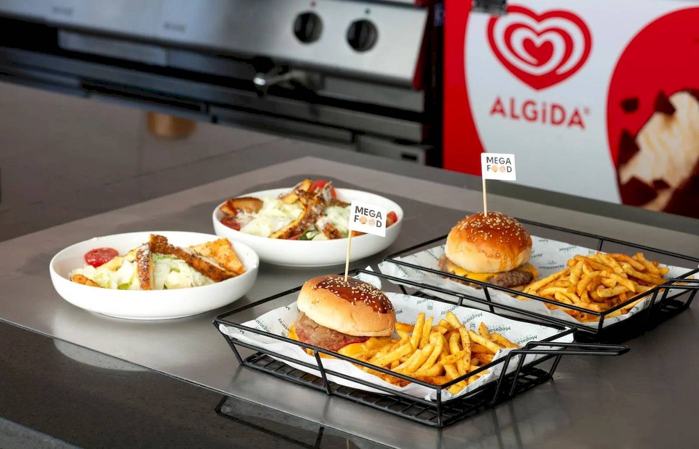 Drei Gerichte von Megasaray Resort Side: Burger, Pommes und Salat, serviert auf einer Theke.