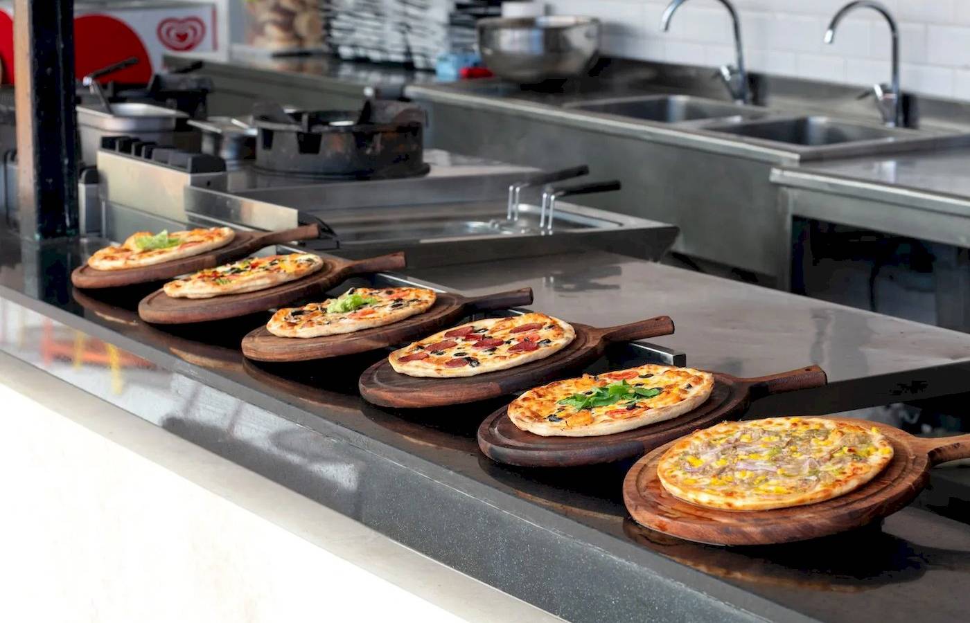 Mehrere Pizzen auf Holzplatten in der Küche des Megasaray Resort Side.