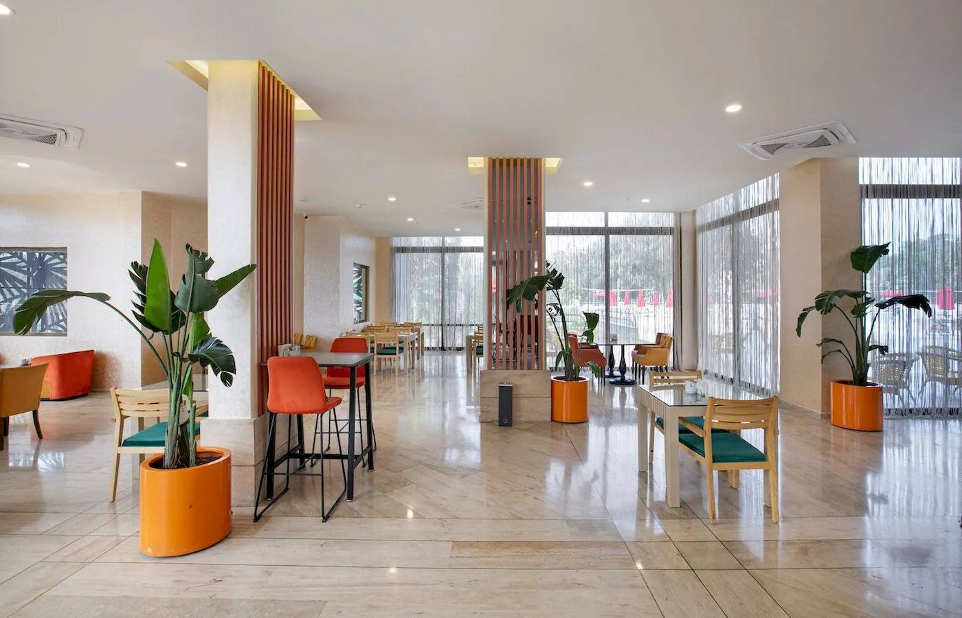 Innenbereich des Megasaray Resort Side mit Tischen, Stühlen und Pflanzen in orangefarbenen Töpfen.