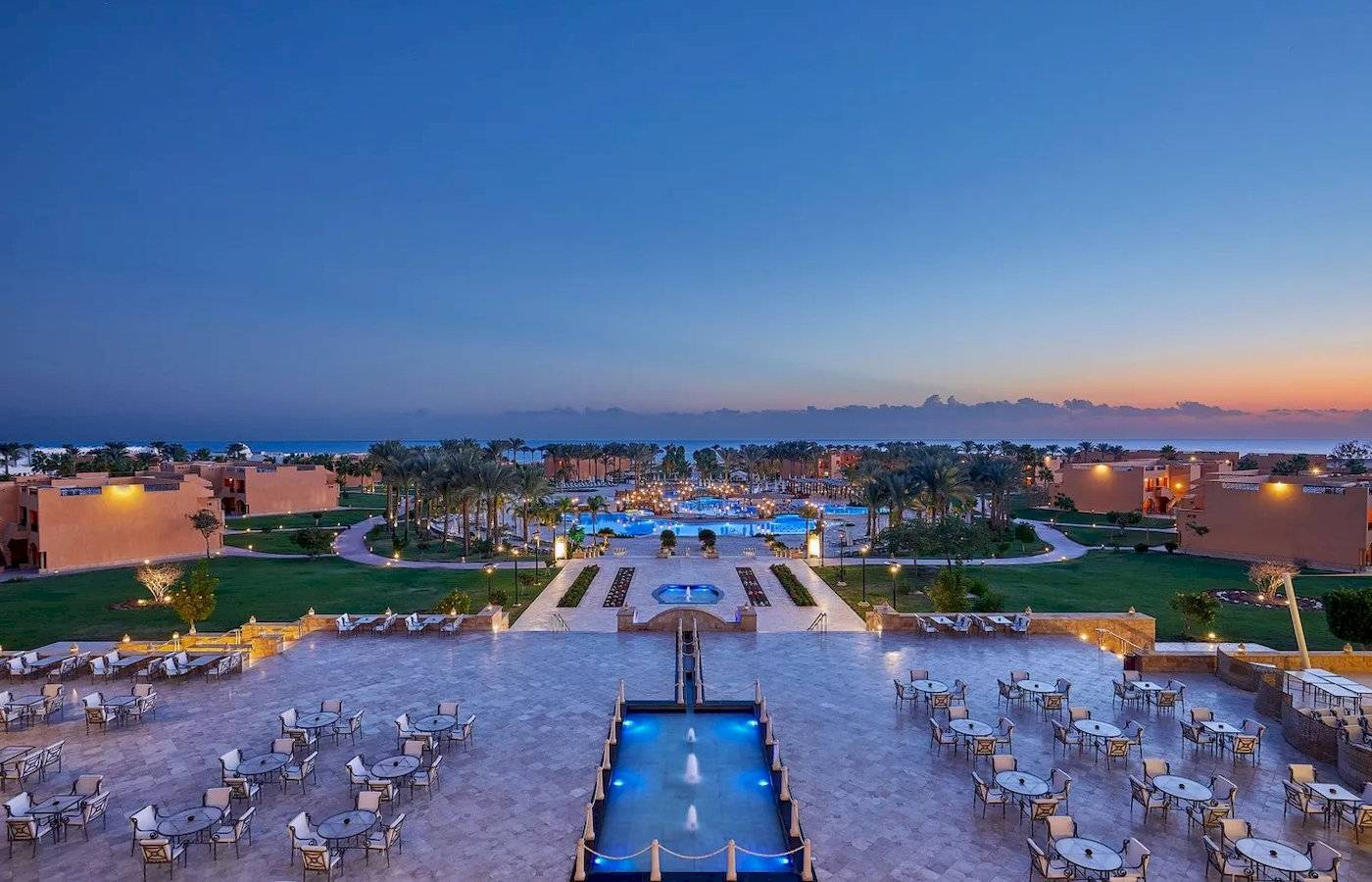 Luftaufnahme des Jaz Grand Marsa Hotels mit Swimmingpools und Außenbereichen bei Sonnenuntergang.