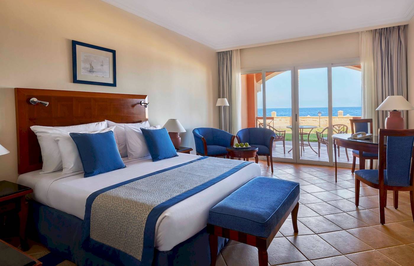 Jaz Grand Marsa Hotel Zimmer mit Meerblick, komfortablem Bett und Sitzbereich.