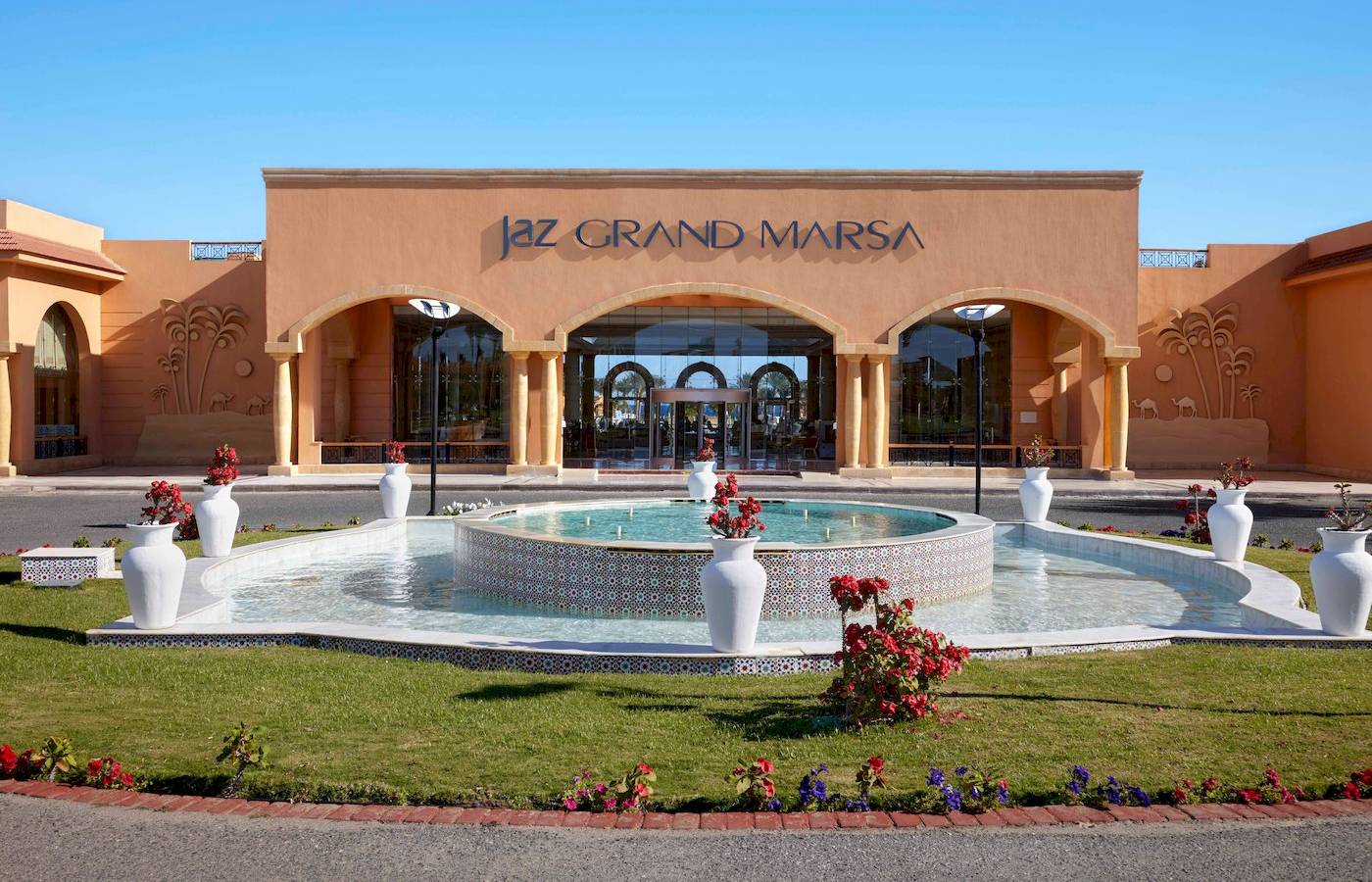 Außenansicht des Jaz Grand Marsa Hotels mit Brunnenanlage vor der Eingangstür.