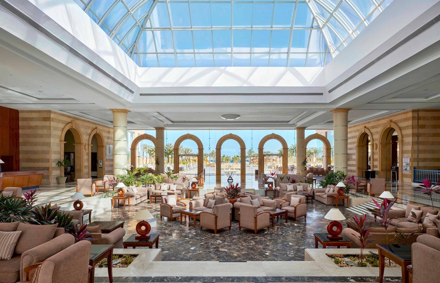 Lobby des Jaz Grand Marsa Hotels mit Glasdach und vielen Sitzgelegenheiten.