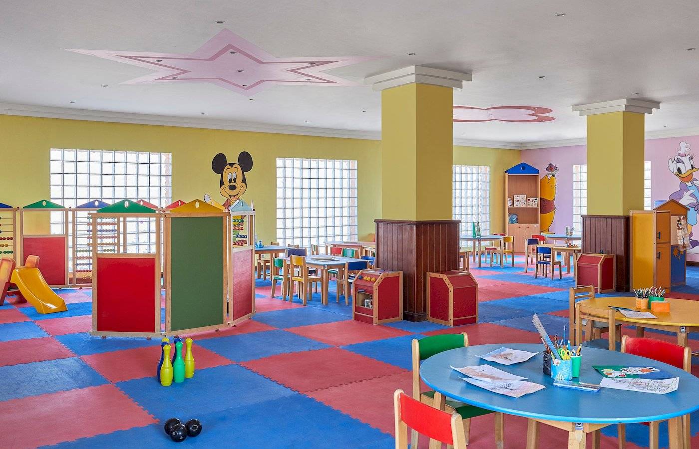 Spielzimmer im Jaz Grand Marsa Hotel mit bunten Teppichen, Disney-Zeichentrickfiguren und Spielzeug.