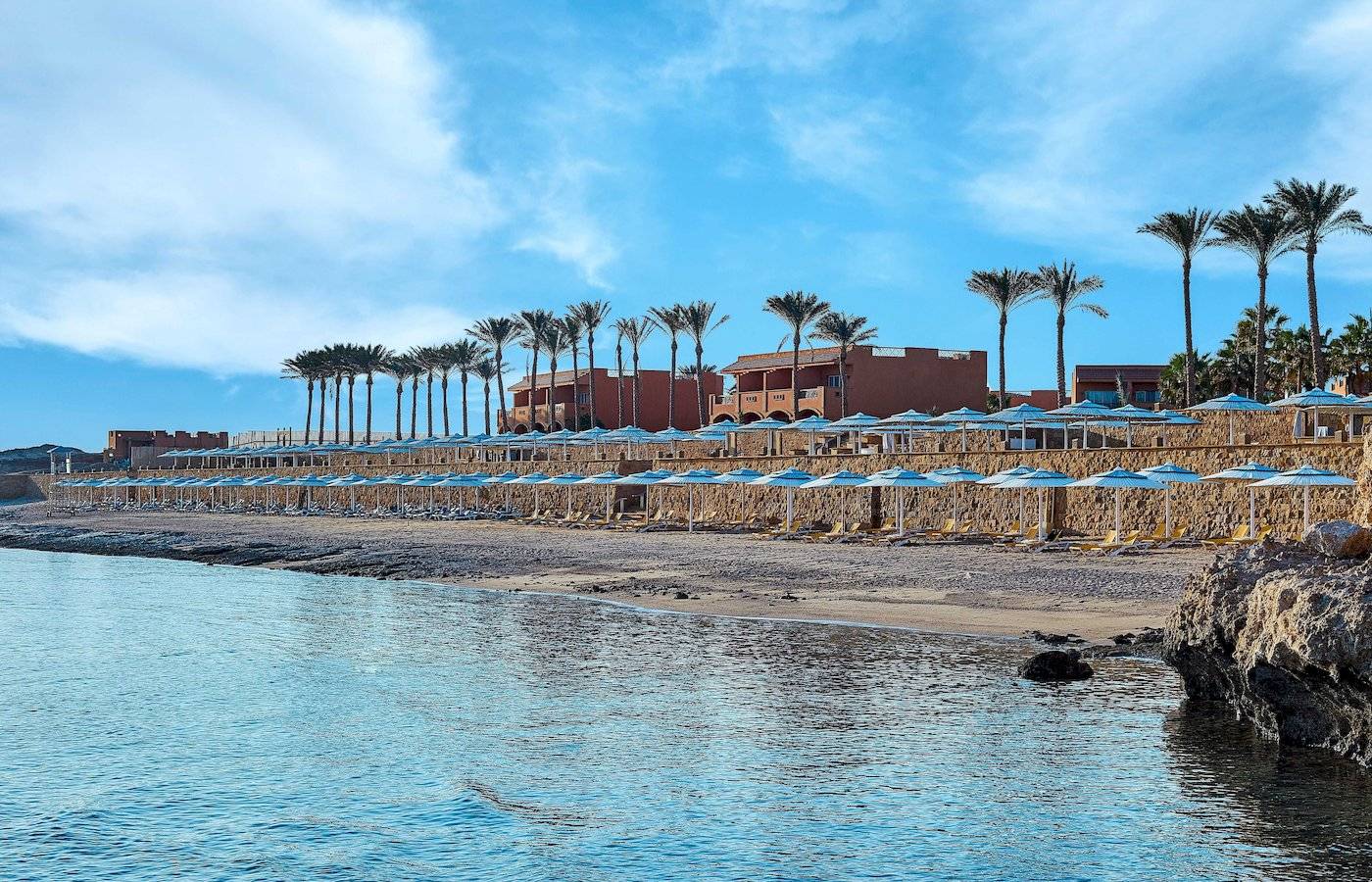 Strand des Jaz Grand Marsa Hotels mit Palmen und Sonnenschirmen