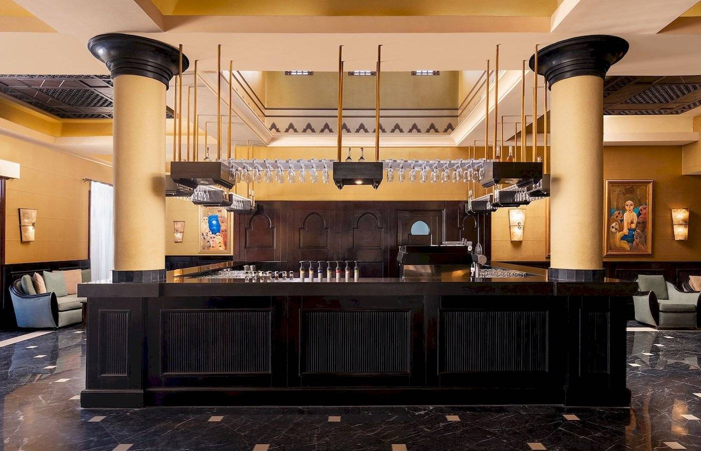 Innenbereich der Bar im Jaz Lamaya Resort Hotel mit schwarzen Theken und hohen Säulen.