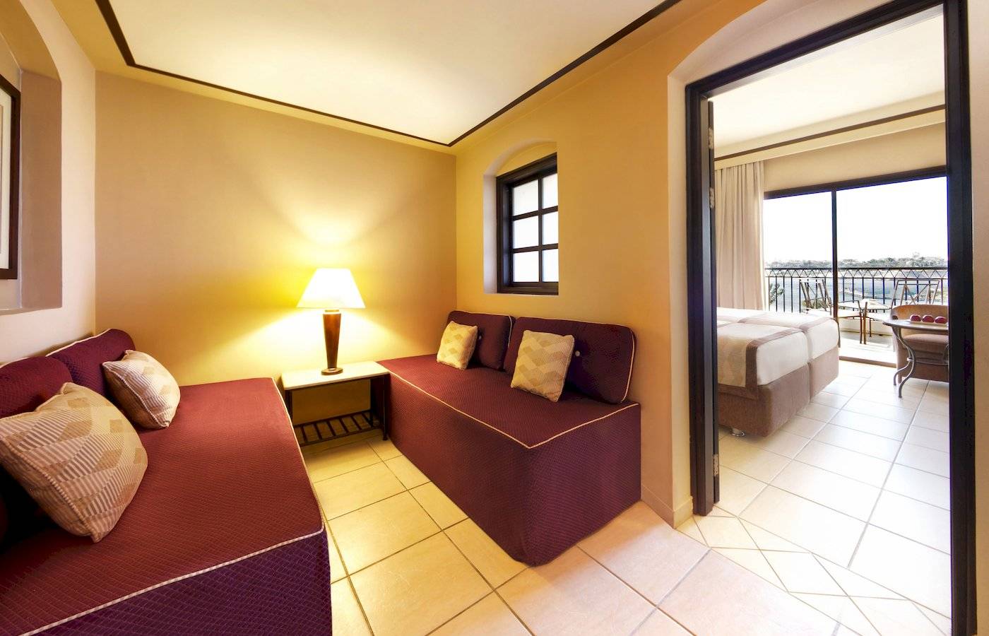 Innenansicht einer Suite im Jaz Lamaya Resort mit zwei Sofas, Tisch und Lampe.