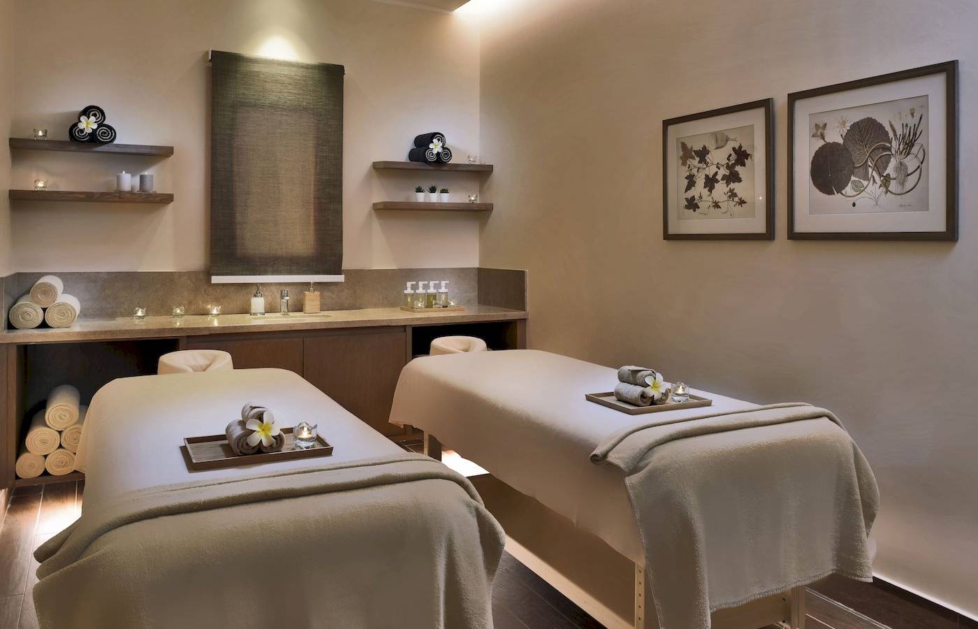 Spa-Behandlungsraum im Jaz Lamaya Resort mit zwei Massagetischen, Kerzen und Pflanzen.