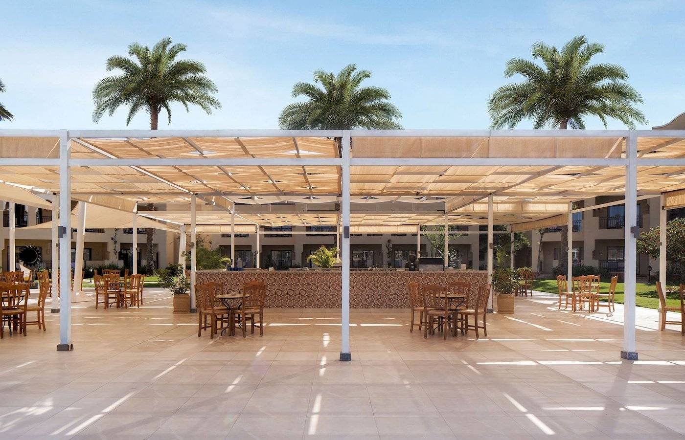 Außenterrasse des Jaz Lamaya Resorts mit Tischen, Stühlen und Sonnenschirmen.