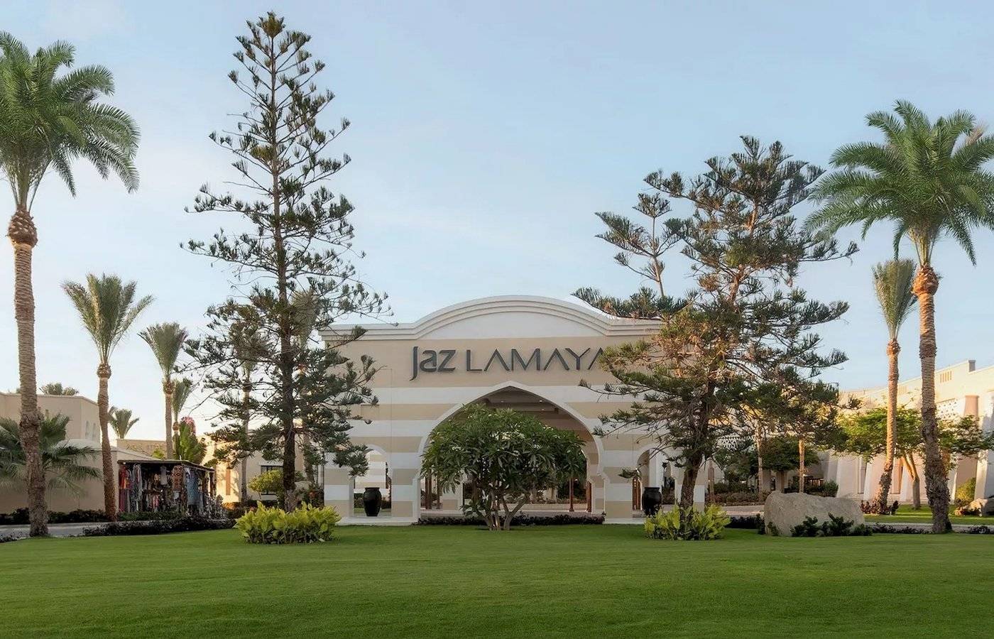 Eingang des Jaz Lamaya Resorts mit Palmen und Rasen.
