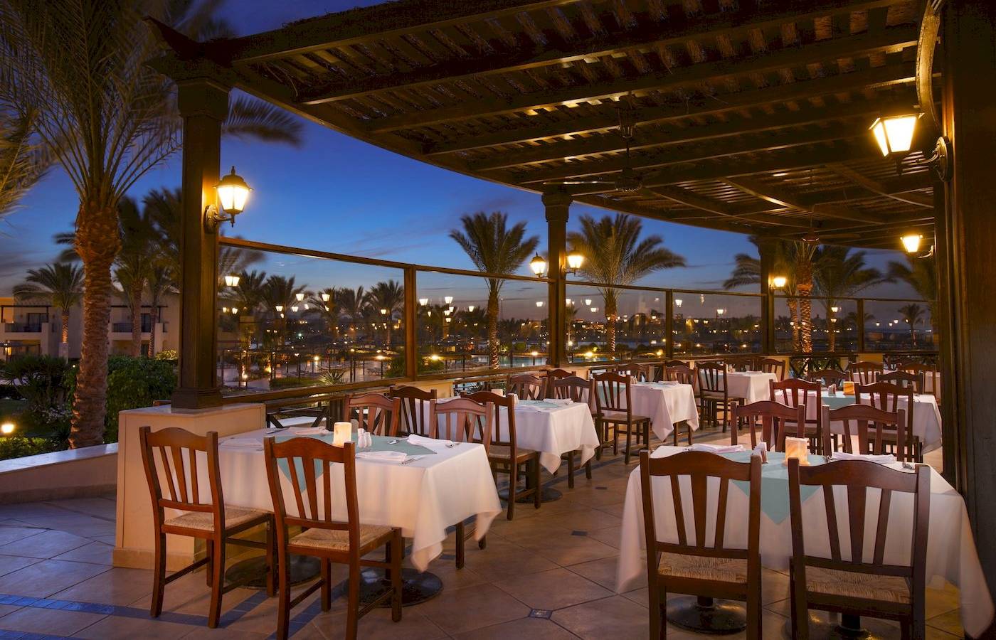 Abendessen auf der Terrasse des Jaz Lamaya Resorts mit gedeckten Tischen und Palmen.