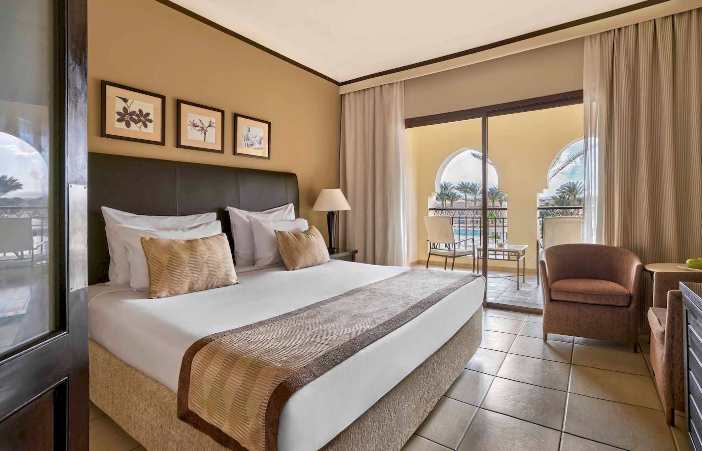 Hotelzimmer im Jaz Lamaya Resort mit bequemem Bett und gemütlichem Balkonzugang.