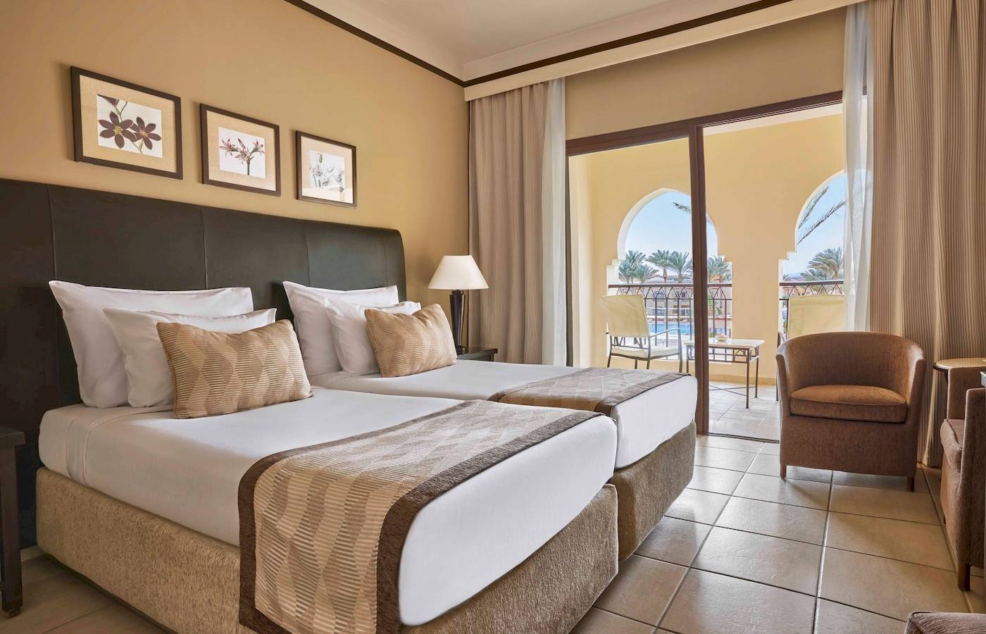 Doppelzimmer im Jaz Lamaya Resort mit zwei Betten und Balkon mit Blick auf den Pool.