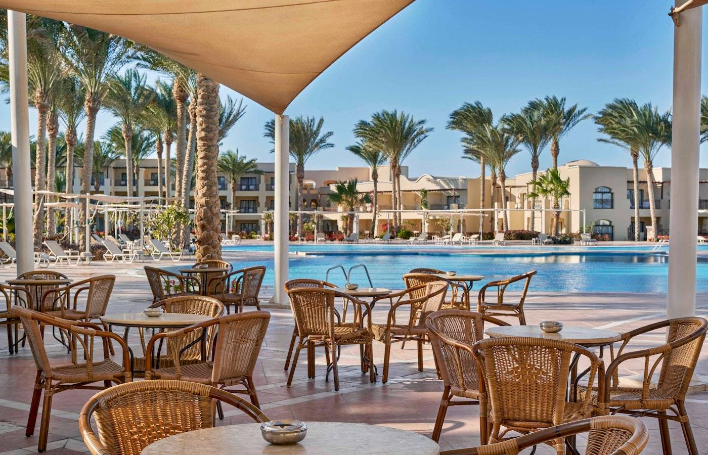 Außenterrasse mit Tischen und Stühlen am Pool im Jaz Lamaya Resort