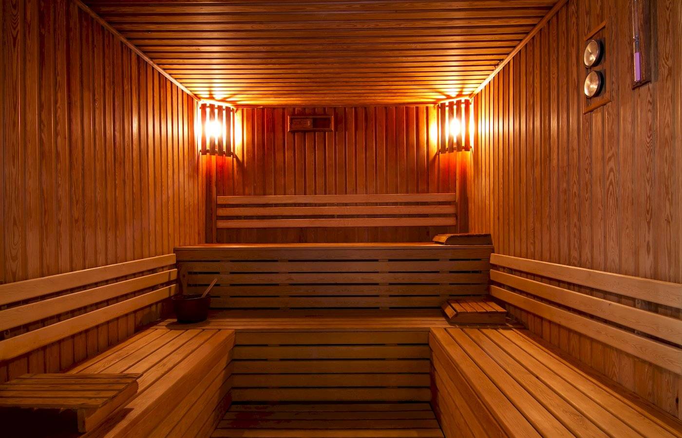 Eine leere Holzsauna mit warmem Licht und Hockern im Jaz Lamaya Resort