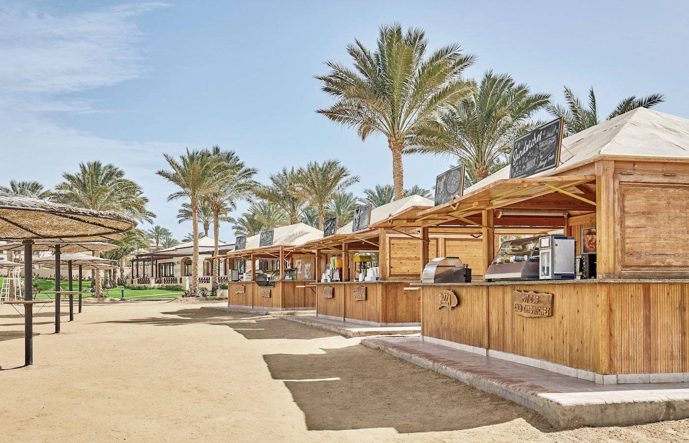 Strandimbissbuden im Jaz Lamaya Resort mit Holzhütten und Palmen im Hintergrund.