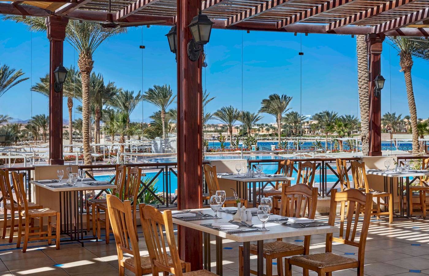 Terrassenrestaurant im Jaz Lamaya Resort mit Tisch und Stuhl vor einem Pool.
