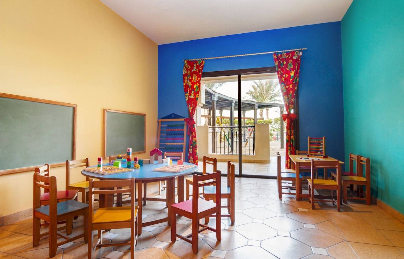 Kinderzimmer im Jaz Lamaya Resort mit bunten Wänden und Spieltischen.