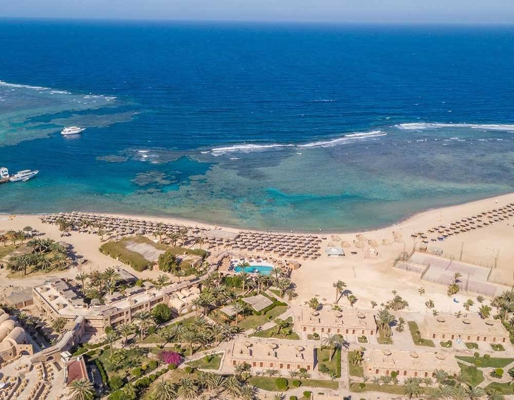 Utopia Beach Club Außenansicht mit Strand, Meer und Gebäuden.