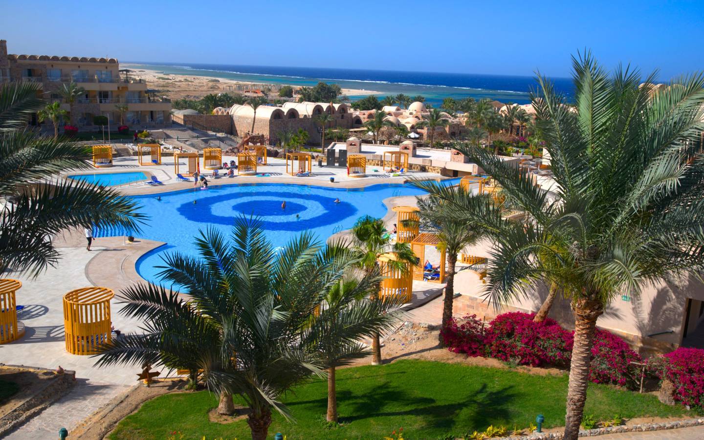 Luftaufnahme des Utopia Beach Club Resorts mit Swimmingpool und Meer im Hintergrund.