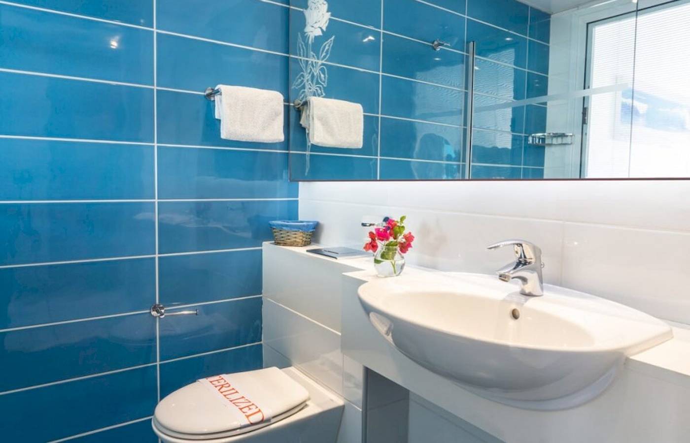 Blaue Fliesen Badezimmer mit Toilette und Waschbecken in einem anonymen Hotel