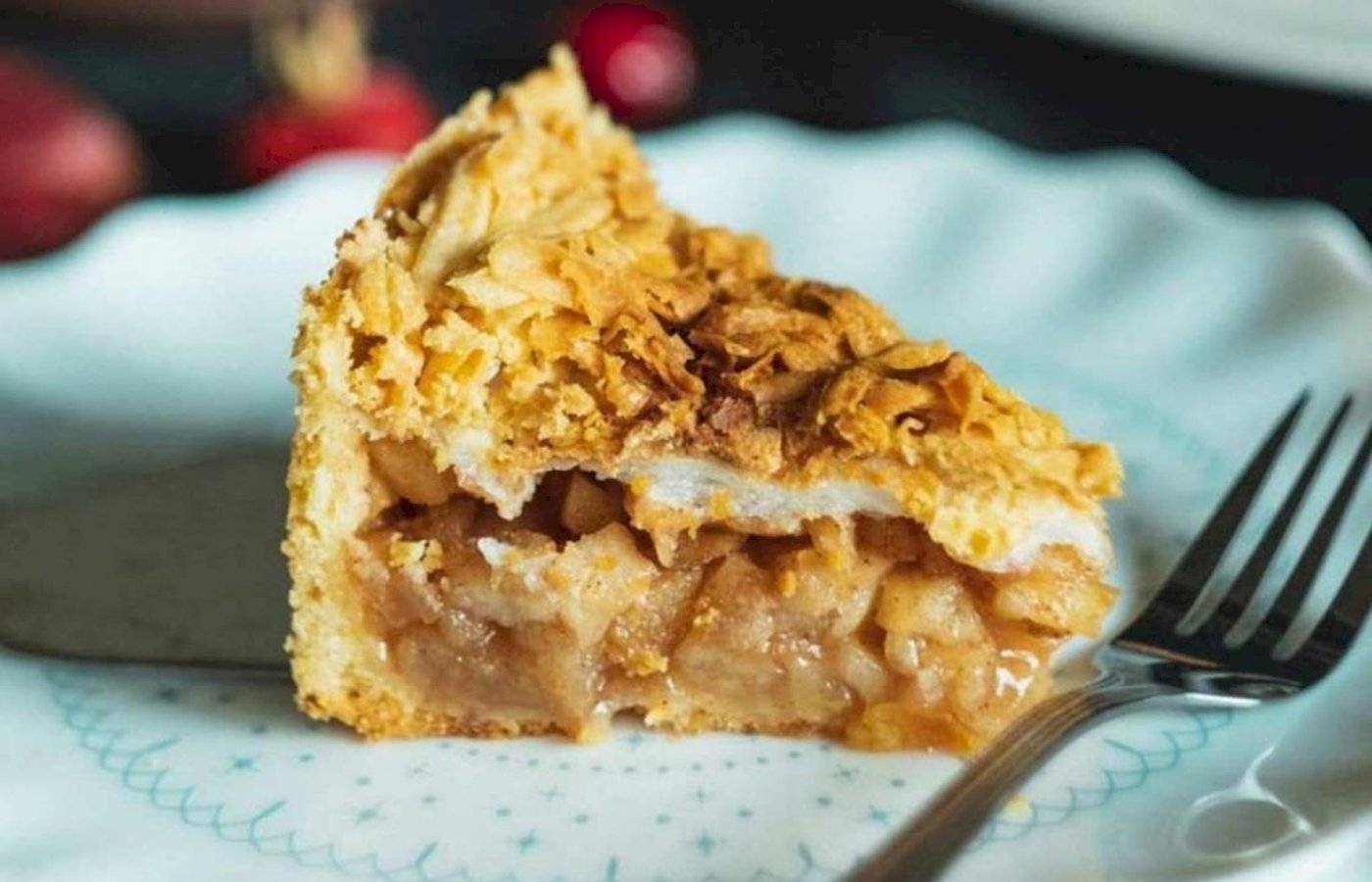 Eine Schnitte Apfelkuchen auf einem Teller mit einer Gabel.