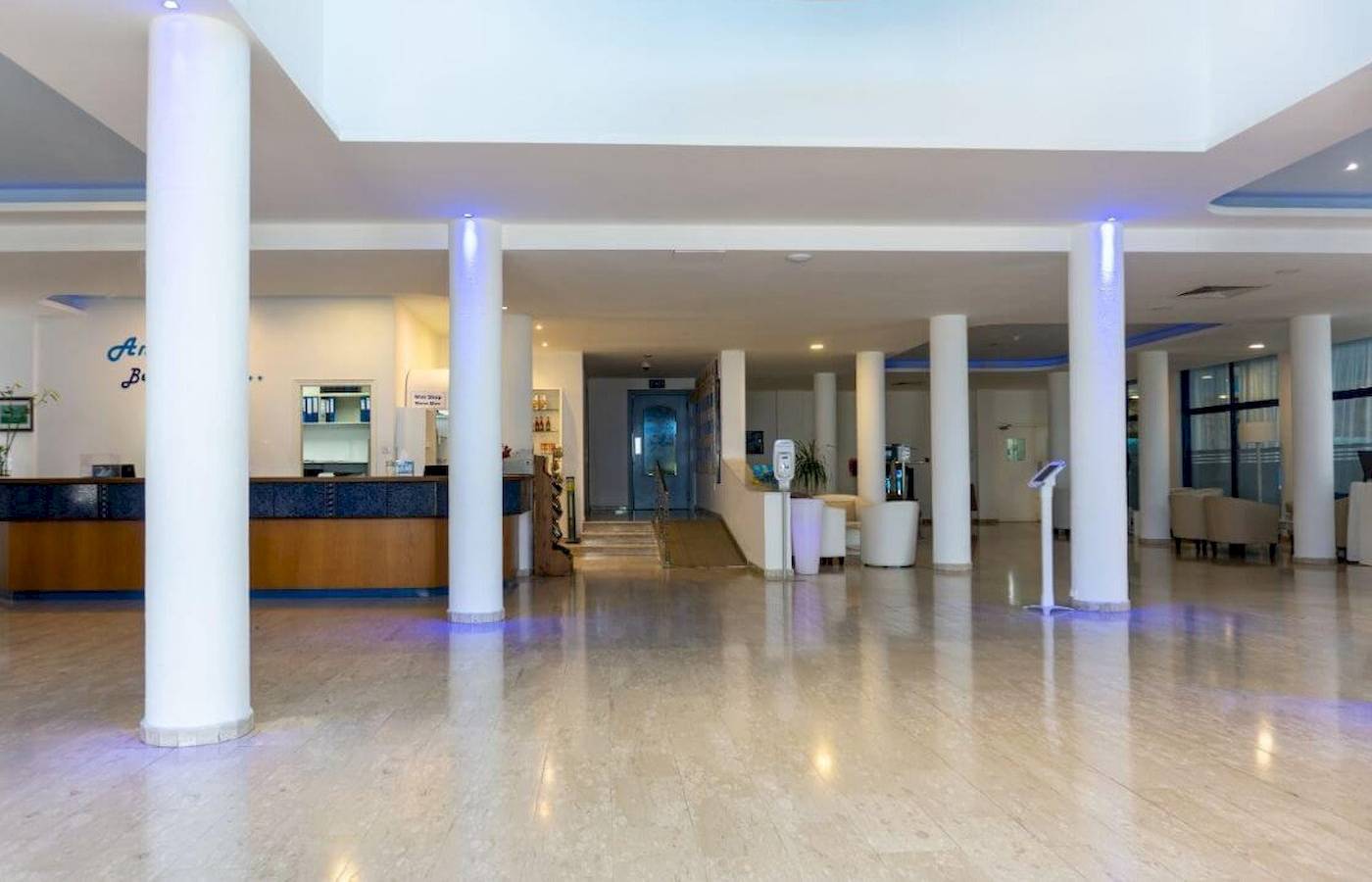 Lobby des Anonymous Beach Hotels mit Empfangstresen, weißen Säulen und Sitzbereich.