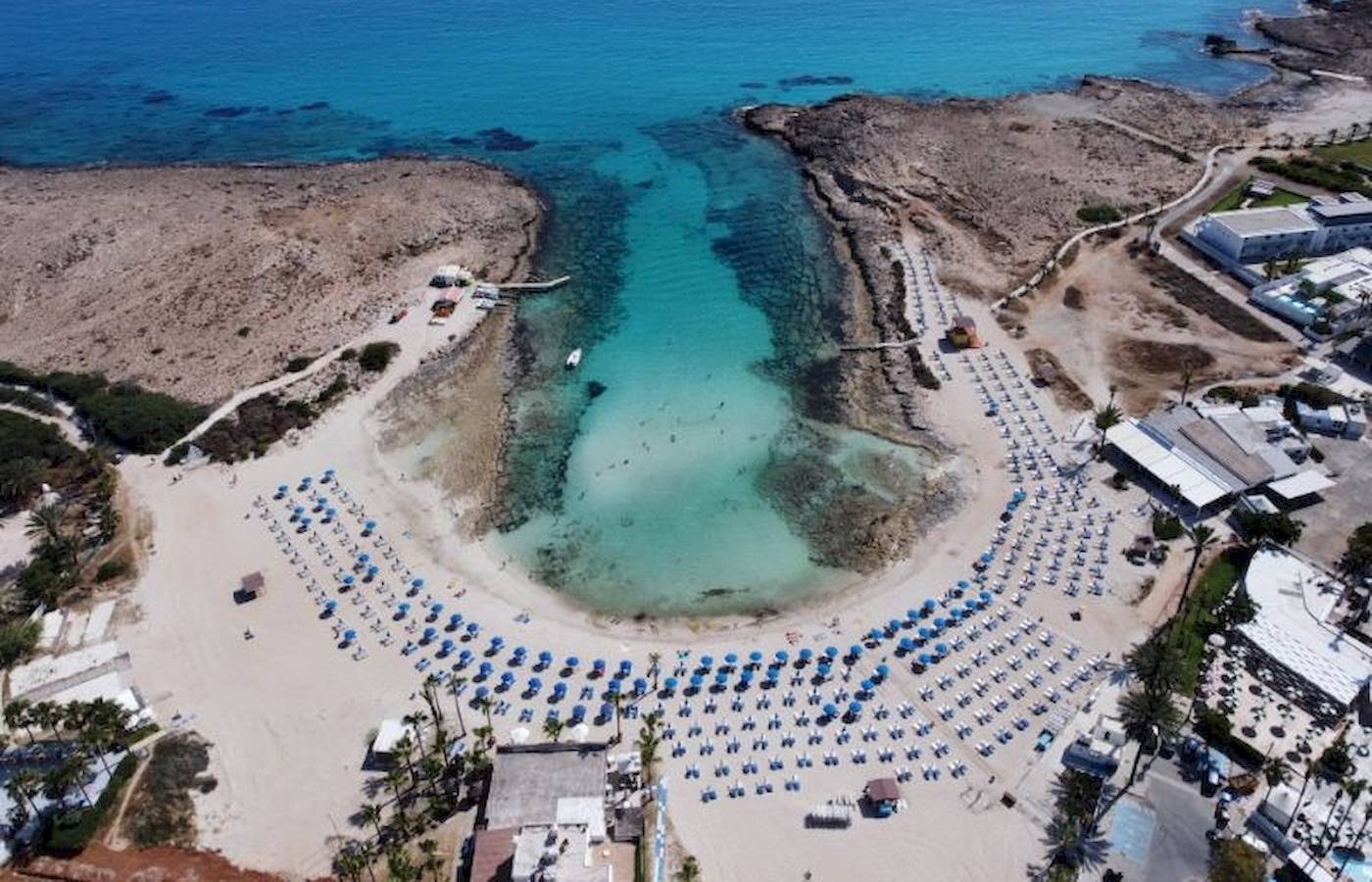 Luftaufnahme des Anonymous Beach mit blauem Wasser und vielen Liegestühlen