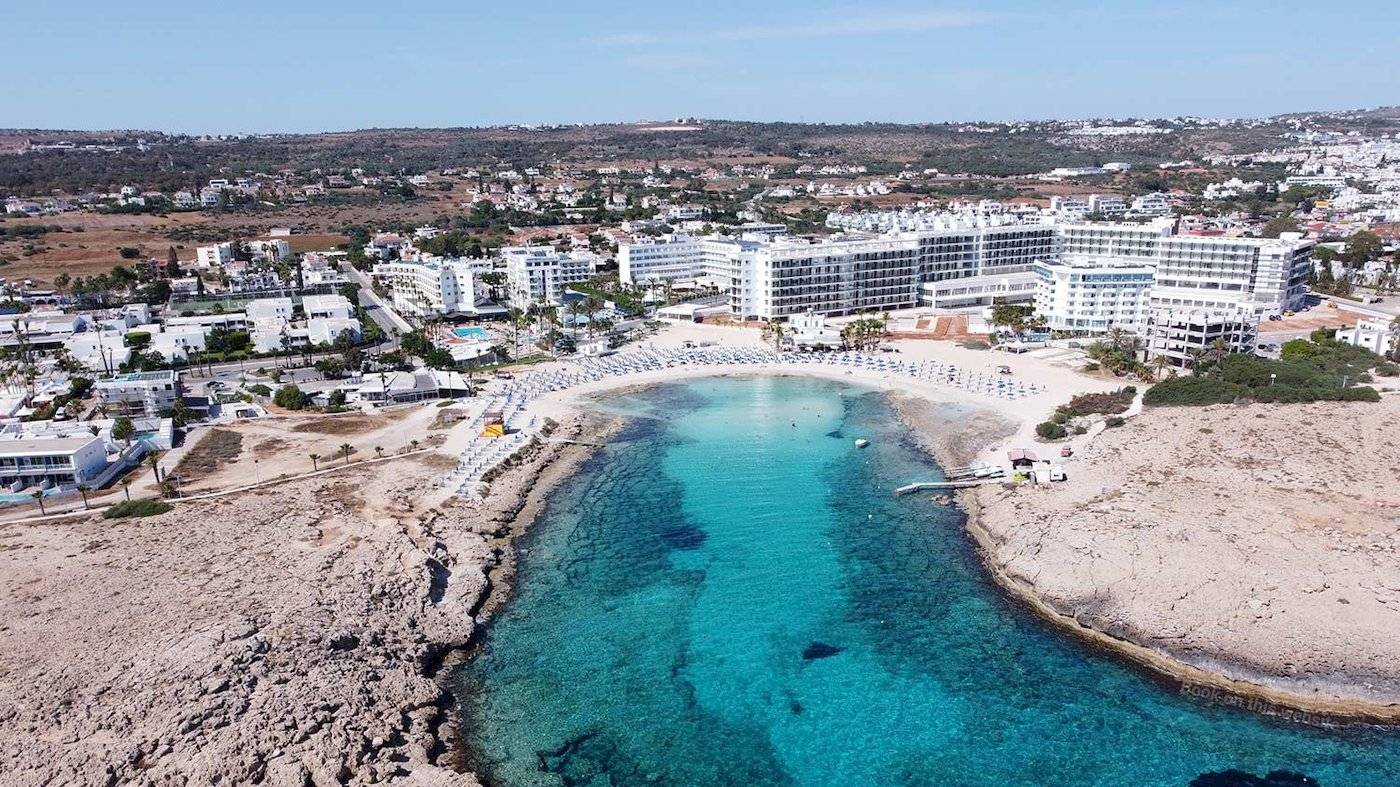 Luftaufnahme des Anonymous Beach Hotels mit Blick auf den Strand, Gebäude und kristallklares Wasser.