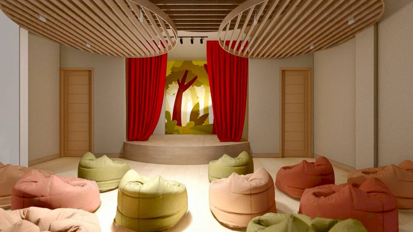 Innenansicht eines Theaters mit roten Vorhängen, Bühne und farbigen Bean Bags.