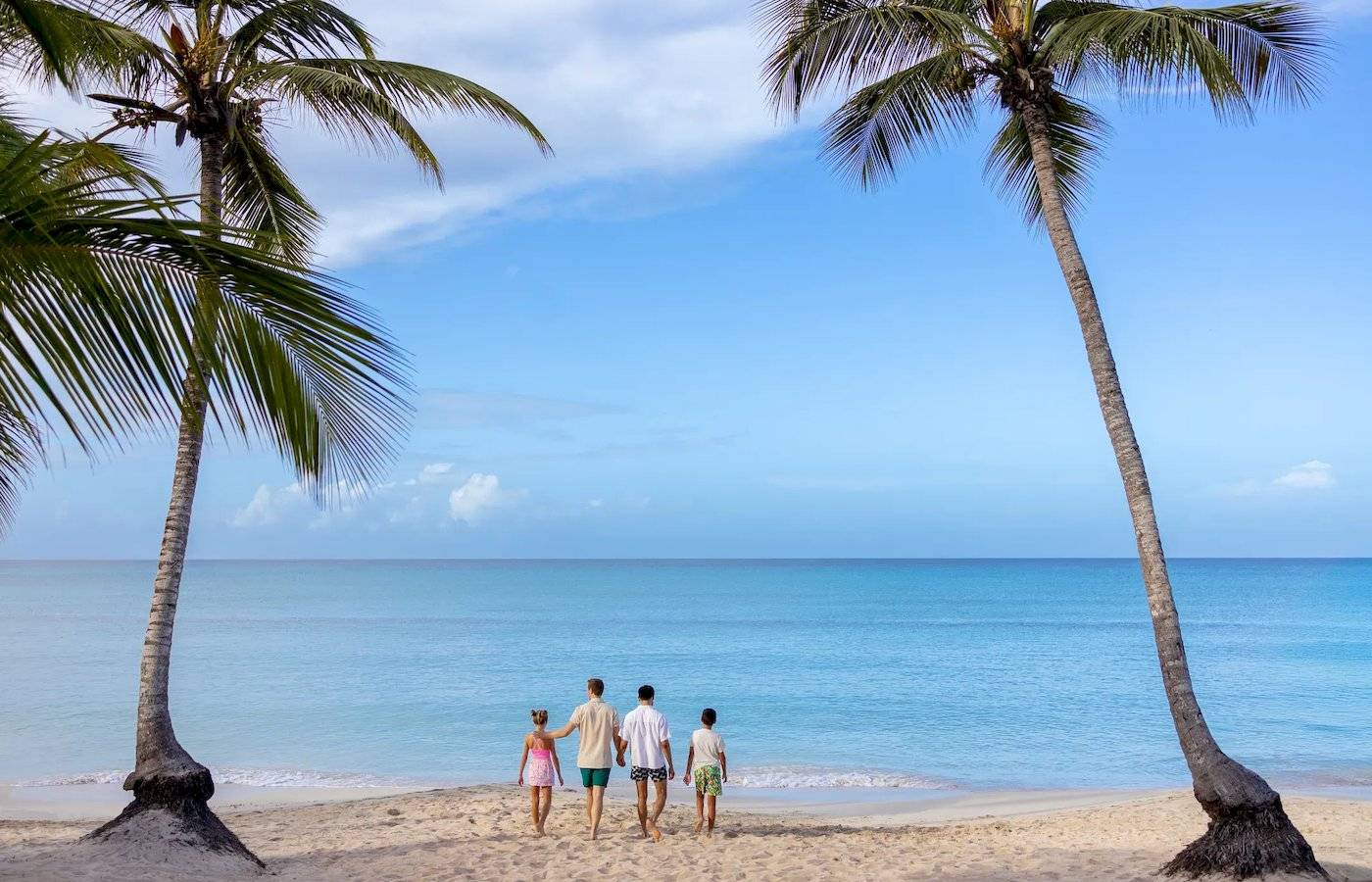 Familie am Strand mit Palmen und blauem Ozean im Hintergrund