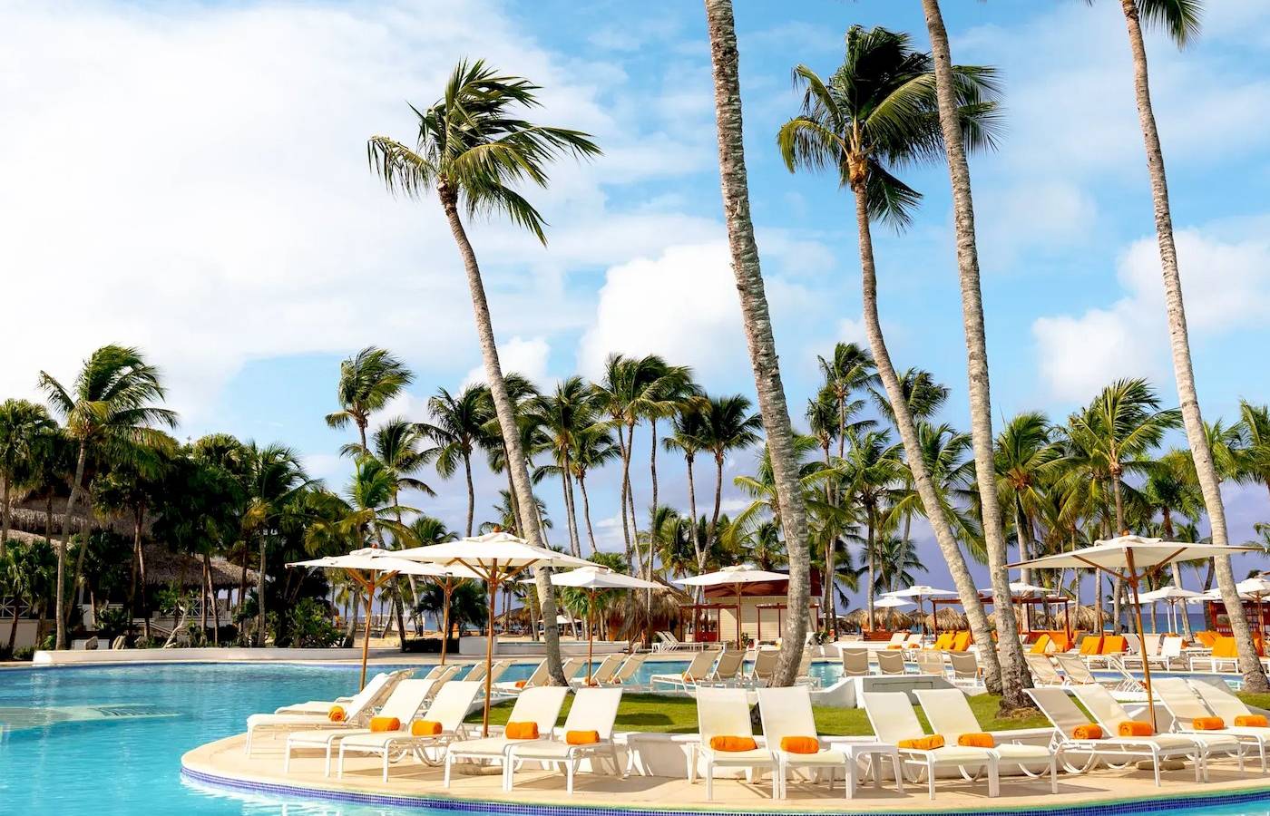Ein Swimmingpool im Sunscape Dominicus La Romana Hotel mit vielen Palmen und Sonnenliegen.