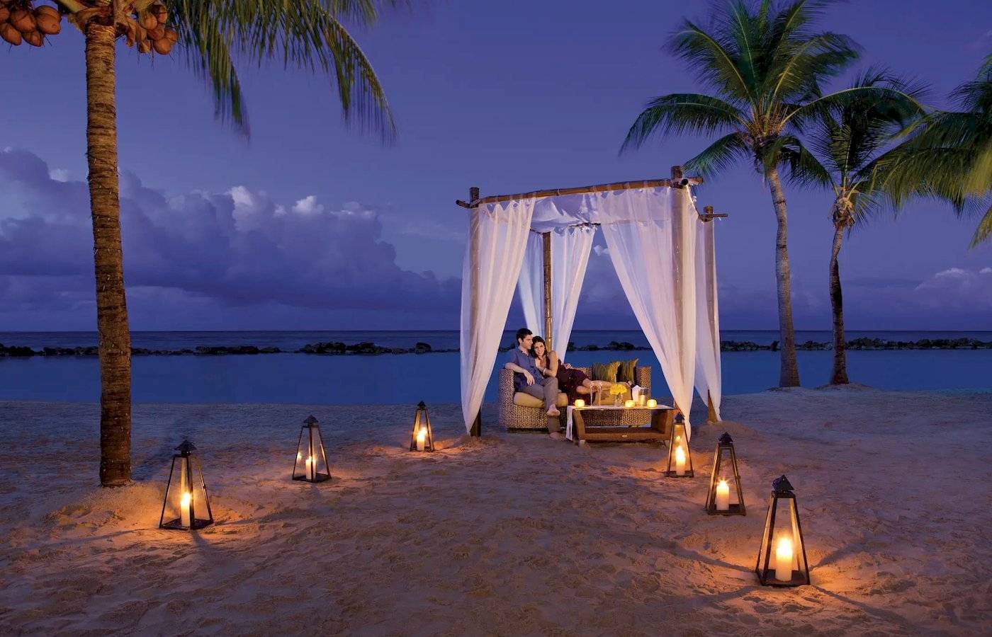 Paar genießt romantische Nacht am Strand unter Sternen mit Zelt und Laternen